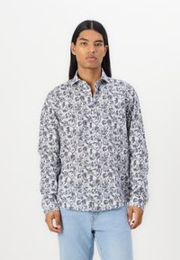 Langermet skjorte i hvit stoff med marineblå blomsterdesign, med klassisk krage og knappefront. Kombinert med lyseblå jeans.