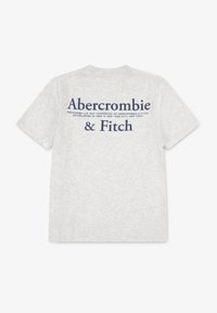 T-shirt grigia in cotone con la scritta "Abercrombie & Fitch" stampata in blu scuro sul retro. Maniche corte e scollo classico a girocollo.