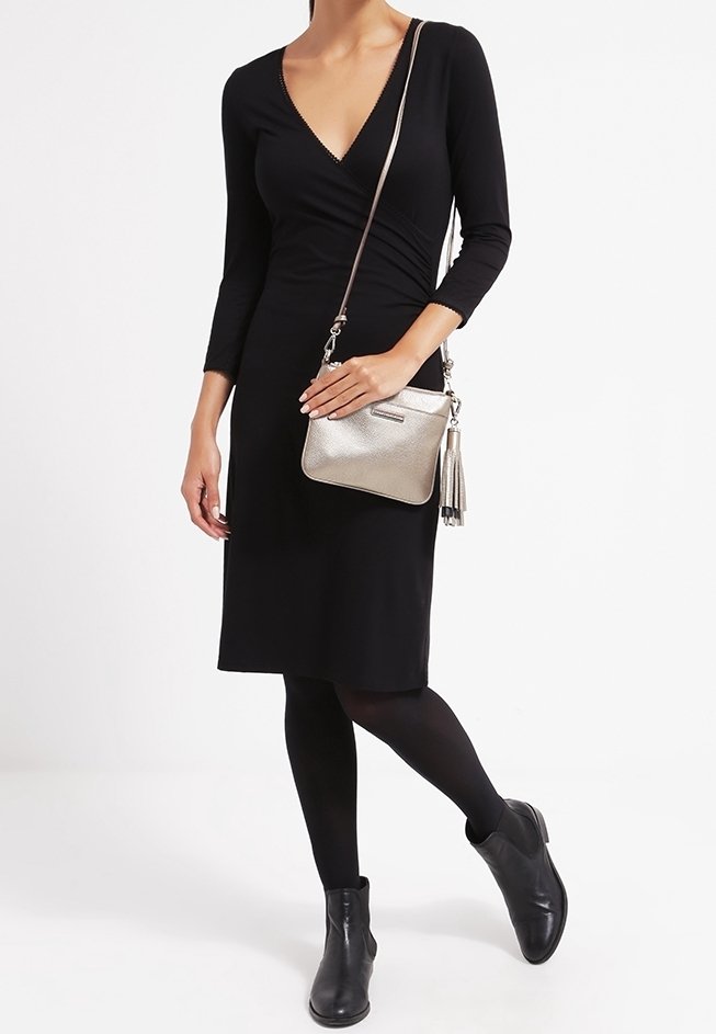 Sort omslagskjole med trekvartærmer, parret med en metalisk sølv crossbody taske med frynser og sorte ankelstøvler.