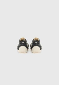 Black sneakers with a textured design, cream accents, and a raised heel. Number "79" printed on the back. Thick rubber sole with grip pattern.