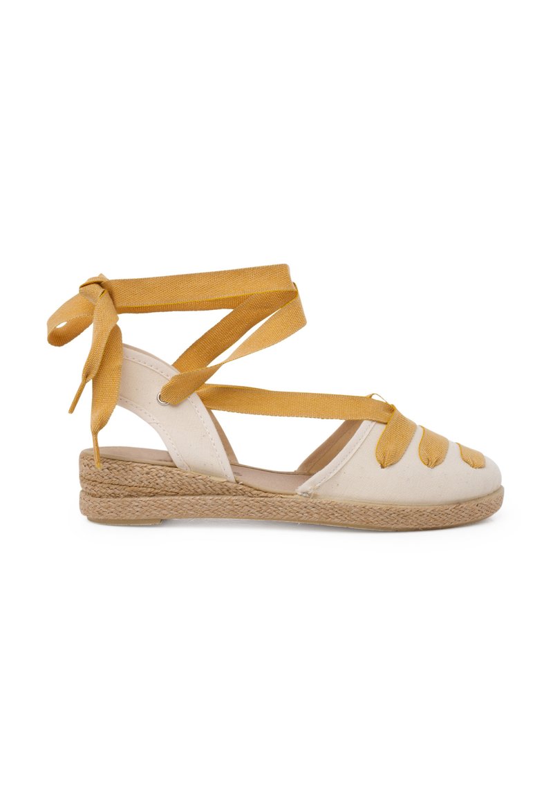 Bílé plátěné espadrilky s pletenou jutu podrážkou, s žlutými látkovými popruhy, které se omotávají kolem kotníku a dekorativními uzlovými detaily.