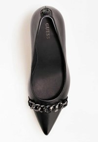 Chaussure plate noire à bout pointu en cuir lisse, ornée d'une chaîne décorative sur le devant et d'un logo subtilement embossé sur la semelle.