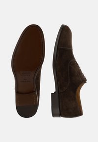 Scarpe eleganti da uomo in suede marrone scuro con lacci, una scarpa mostrata di lato, l'altra mostrata con la suola sopra, con marchio e indicazioni della taglia.