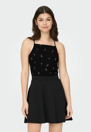 Camisola nera con spalline sottili, caratterizzata da un design testurizzato a costine e ricami floreali argento, abbinata a una gonna nera a vita alta.