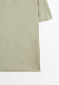 T-shirt verde chiaro in cotone a maniche corte, caratterizzato da una texture morbida, orlo dritto e dettagli di cucitura minimali.