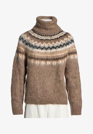 Brązowy, puszysty sweter z golfem z wielokolorowym wzorem Fair Isle na piersiach i ramionach, noszony na białych spodniach.