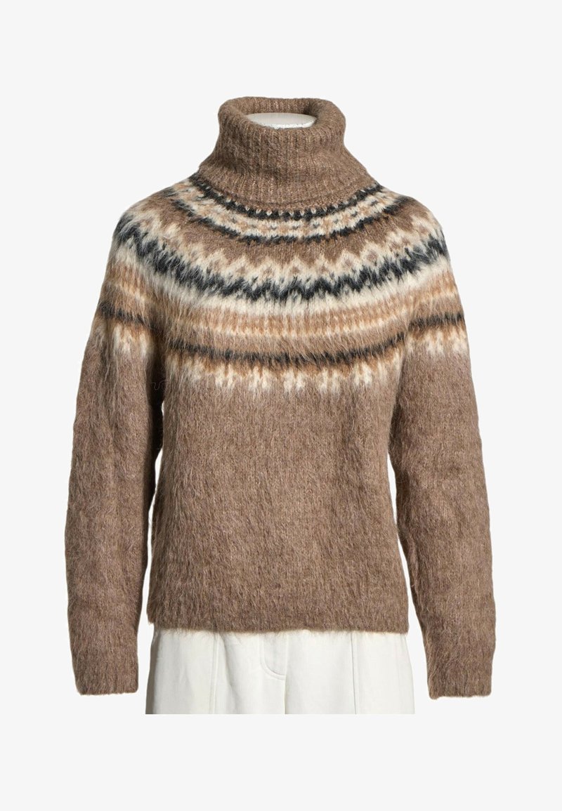 Pull à col roulé marron duveteux avec un motif Fair Isle multicolore sur la poitrine et les épaules, porté par-dessus un pantalon blanc.