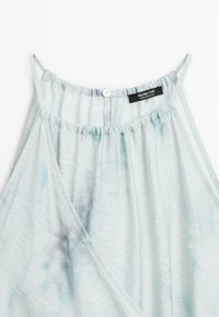 Caraco en satin bleu clair avec fines bretelles, encolure froncée, fermeture à un bouton au dos, et étiquette Massimo Dutti à l'intérieur.