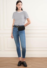 T-shirt a righe a maniche corte, jeans skinny in denim blu, borsa a tracolla in pelle nera e mocassini neri chunky completano l'outfit.