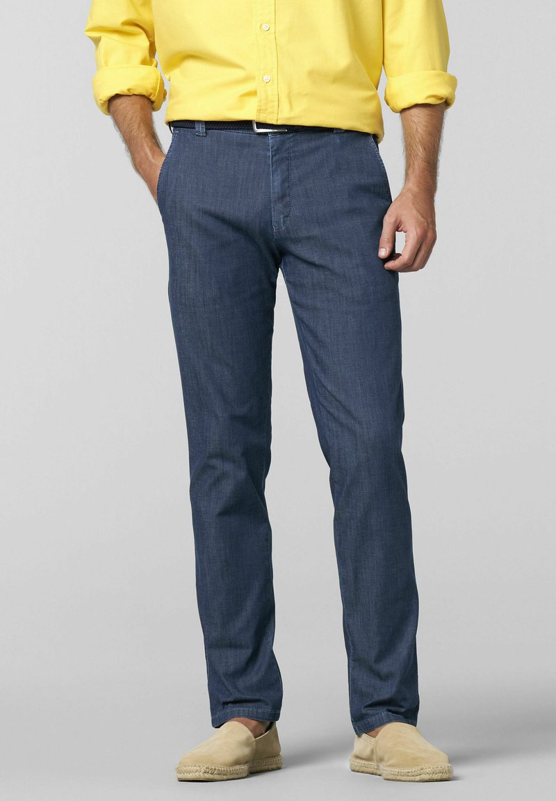 Marineblå chinos med lige snit og sidelommer, parret med en gul knap-op skjorte og beige espadriller. Glat stoftekstur.