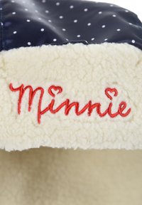 Navy polka dot fabric with a fluffy cream fleece lining; features embroidered red text "Minnie" with heart accents.