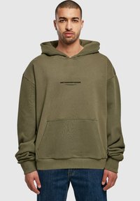 Hoodie vert olive avec une poche kangourou à l'avant, coupe oversize, poignets côtelés et un logo imprimé "MÉTAMORPHOSE" sur la poitrine.