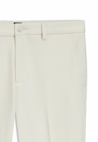 Witte op maat gemaakte broeken van een gestructureerde stof, met een knoopsluiting, riemlussen en zijzakken. Eenvoudig en strak design.