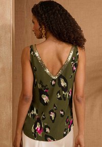 Olive green sleeveless top with a V-neck, featuring a leopard print pattern in black and pink, and a gold sequined neckline accent.