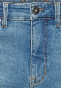 Jeans in denim azzurro chiaro con un classico design a cinque tasche, dotati di un bottone in metallo e cuciture beige lungo le cuciture e nelle tasche.