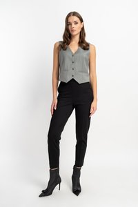 Grauwe sleeveless Weste mit V-Ausschnitt, vorderen Knöpfen, kombiniert mit schwarzen tapered Hosen und spitzen Knöchelstiefeln. Glatter Stoff, taillierte Passform.