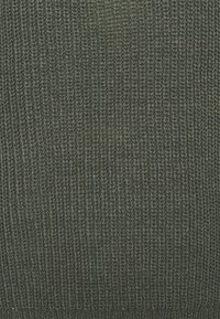 Tissu tricoté vert avec un motif côtelé texturé. Le tricot est d'épaisseur moyenne, présentant des variations subtiles de couleur.