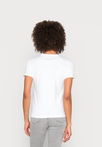 Hvid kortærmet t-shirt lavet af bomuldsblanding, med en klassisk rund halsudskæring og en glat tekstur. Bagansigtet viser skuldersømme og en let kurve i kanten.