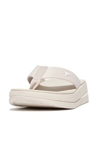 Lichtbeige flip-flop sandaal met gestructureerde stoffen banden en een dikke, gewatteerde zool. Heeft een minimalistisch ontwerp en een subtiele merkinformatie.