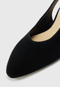 Sort ruskind lukkede sko med spids front og et udskåret sidesnit. Glat tekstur med et minimalistisk udseende.