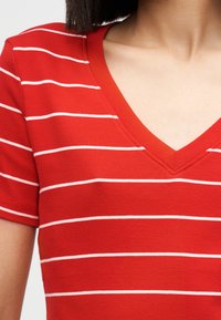 Κόκκινο T-shirt με λευκές οριζόντιες ρίγες, λαιμόκοψη V, κοντά μανίκια και μαλακή, λεία υφή. Απλό και casual στυλ.