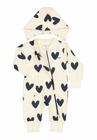 Krämfärgad jumpsuit med marinblå hjärtan i mönster, framsida med dragkedja, lång ärm och matchande huva med tryckknappar. Mjuk tygtextur.