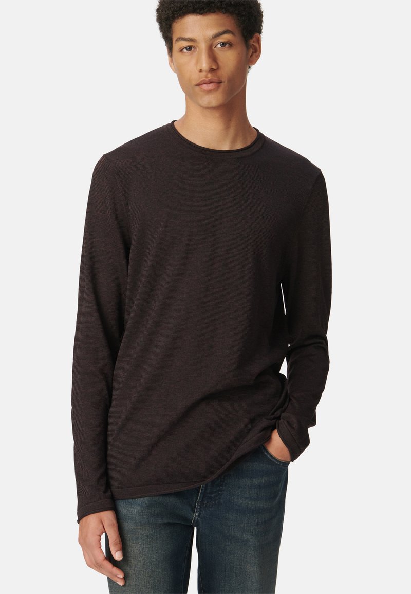 Langärmliges Rundhals-Shirt in dunklem Burgunderrot mit strukturiertem Stoff. Getragen mit lässigen Jeans, zeigt es eine bequeme Passform und ein einfaches Design.