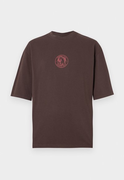 Brūna kokvilnas T-krekls ar īsām piedurknēm, apaļu kakla izgriezumu un sarkanu apļa grafiku ar zirga dizainu un tekstu.