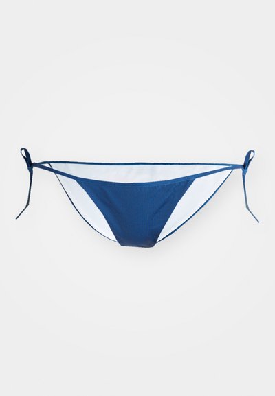 Navy zila bikini apakšda ar baltām sānu malām, ar regulējamiem saitēm atbilstošai izmēru pielāgošanai. Gluda tekstūra un minimāls dizains.