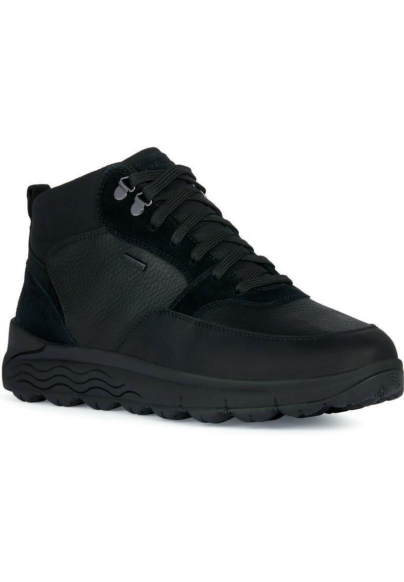 Schwarze High-Top-Schuhe aus einer Mischung aus glattem und strukturiertem Leder, verstärkten Schnürsenkeln und einer flexiblen Gummisohle mit Wellenmuster.