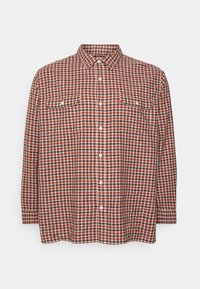Camisa de cuadros en colores rojo, marrón y crema; cuenta con un cierre de botones en la parte delantera, dos bolsillos en el pecho y un cuello clásico.