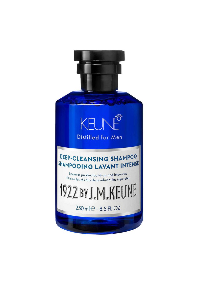 Bottiglia di vetro blu con un tappo nero. L'etichetta presenta "SHAMPOO PROFONDO PULENTE" e "1922 DI J.M. KEUNE." Volume: 250 ml.