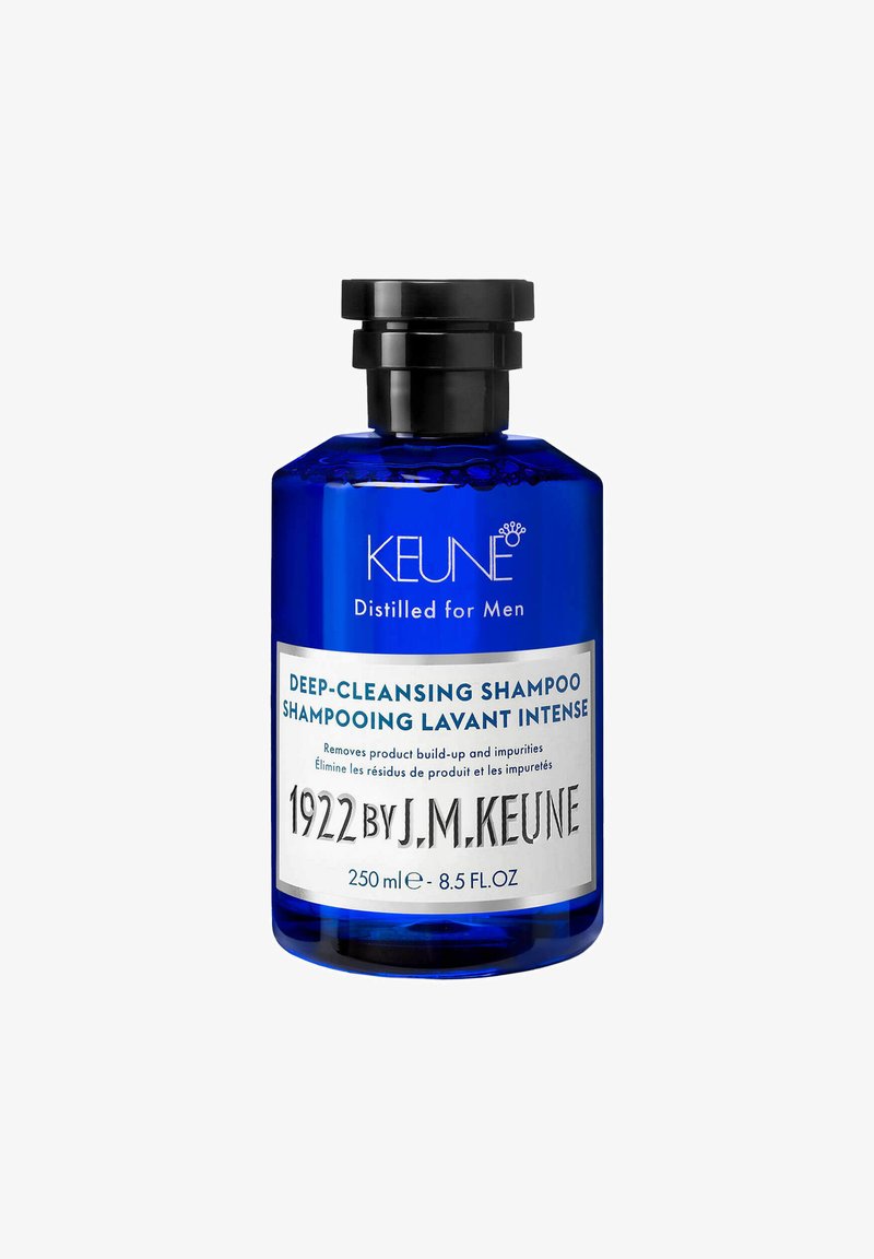 Bottiglia di vetro blu con un tappo nero. L'etichetta presenta "SHAMPOO PROFONDO PULENTE" e "1922 DI J.M. KEUNE." Volume: 250 ml.