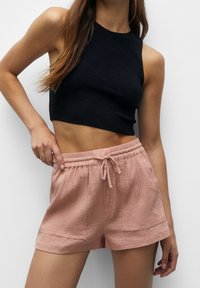 Top corto a coste nero abbinato a pantaloni corti rosa con texture, dotati di vita elastica e tasche frontali.
