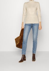 Beige kaulusneule, vaaleansiniset slim fit -farkut, ruskeat korkokengät nilkkurit ja ruskea keinoturkislaukku. Sileät pinnat ja istuva muotoilu.