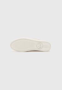 Semelle de sneaker en caoutchouc blanc avec une surface texturée, présentant un logo circulaire et des motifs de lignes horizontales pour un meilleur grip et des détails de design.