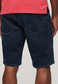 Ciemnoniebieskie szorty dżinsowe o prostym kroju, z tylnymi kieszeniami i długości do połowy uda, z subtelnymi detalami w szwie.