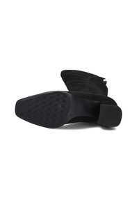 Zwarte suède enkelboot met een spitse neus en unieke ribbelstructuur. Beschikt over een rubberen zool met een hexagonaal grippatroon.