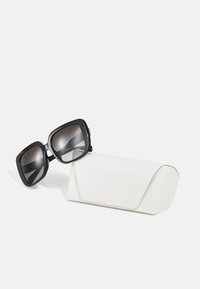 Ochelari de soare mari, de culoare neagră, cu lentile gradient, având colțuri rotunjite, și o carcasă dură texturată de culoare albă, embosată cu "MICHAEL KORS."