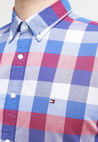 Hemden mit Knopfleiste in einem karierten Muster aus Blau-, Rot- und Weißtönen. Aus Baumwolle gefertigt, mit einem kleinen Logo nahe dem Saum.