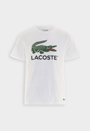 Witte katoenen t-shirt met een groen krokodil logo en zwarte "LACOSTE" tekst op de voorkant, korte mouwen en een ronde halslijn.