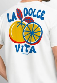 Weißes T-Shirt mit einem grafischen Design von einer gelben Orange und Limette, mit blauer Schrift "LA DOLCE VITA" und roten Blättern.
