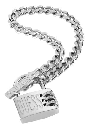 Srebrna bransoletka łańcuchowa z zawieszką w kształcie kłódki z wygrawerowanym napisem "GUESS" i ozdobiona małymi kryształowymi akcentami.