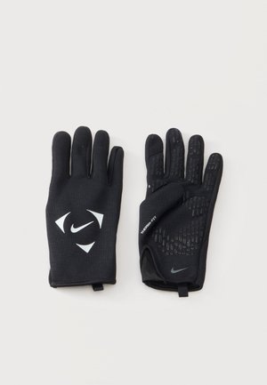 Paire de gants Nike noirs avec une prise texturée sur les paumes et des logos Nike blancs au dos et aux poignets, posés à plat sur une surface claire.
