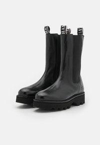 Black leather ankle boots with elastic side panels and pull tabs. Features a chunky rubber sole with a textured tread design.