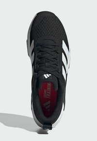 Black training shoe with a mesh upper, featuring white stripes and a red insole. Textured design with black laces and a rubber sole.