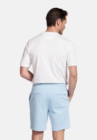 White short-sleeve shirt with a straight cut and a plain design, paired with light blue shorts featuring two back pockets and a smooth texture.