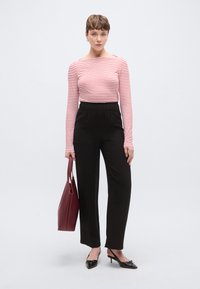 Μπλούζα μακρυμάνικη με κόκκινες και λευκές ρίγες συνδυασμένη με μαύρο παντελόνι ψηλόμεσο. Κρατάει μπορντό τσάντα ώμου και φοράει μαύρα παπούτσια με τακούνι.