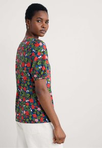 Haut à manches courtes imprimé floral en marine, ornée de fleurs rouges et roses avec des feuilles vertes. Col rond et coupe décontractée avec des manches légèrement bouffantes.