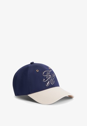 Cappellino da baseball blu navy e beige con logo "TH" in corsivo ricamato sul davanti e occhielli dorati sui pannelli superiori.